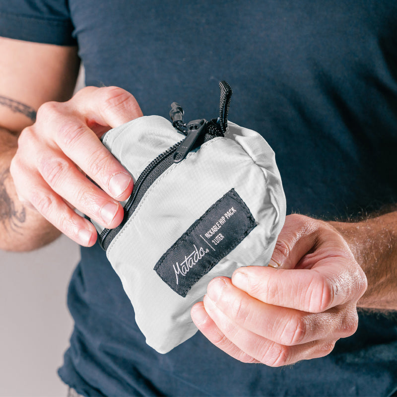 Man holding close up shot of packed down white sling bag