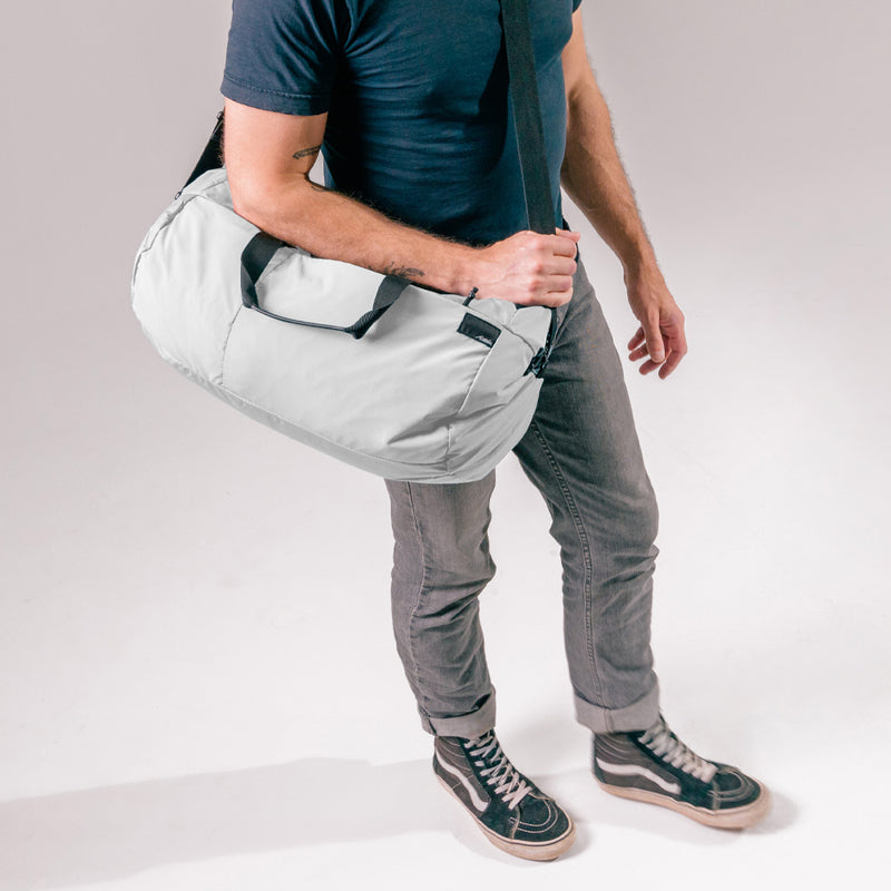 man wearing arctic white duffle over his shoulder and across his body