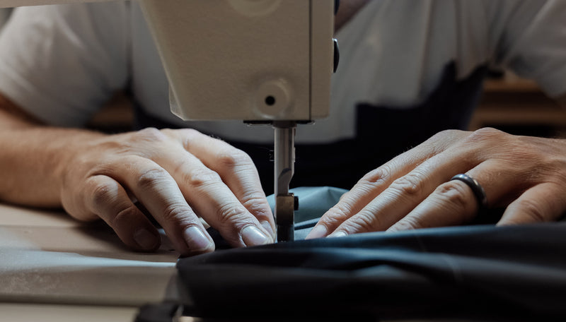 Close up of hands working fabric through sewing machine