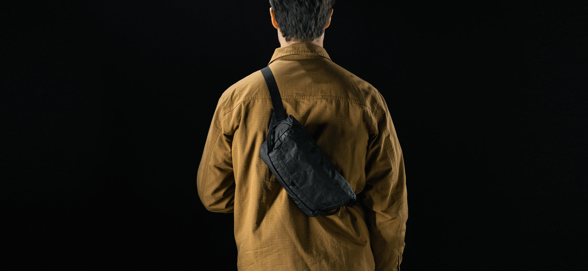 man in black studio wearing black sling across his back