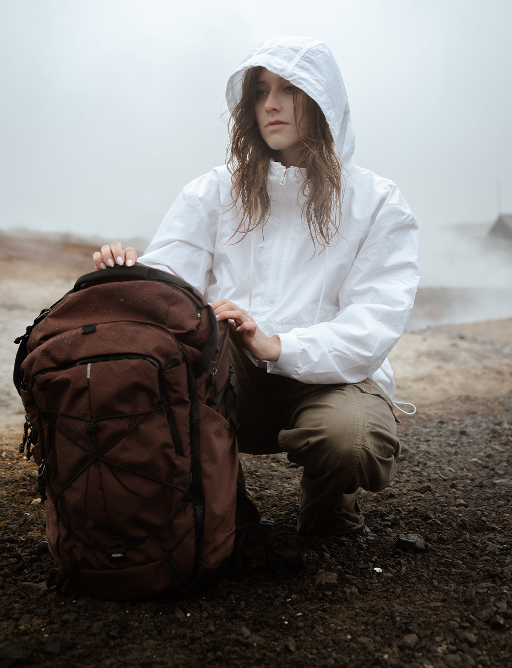 person in white jacket crouching down in rainy setting