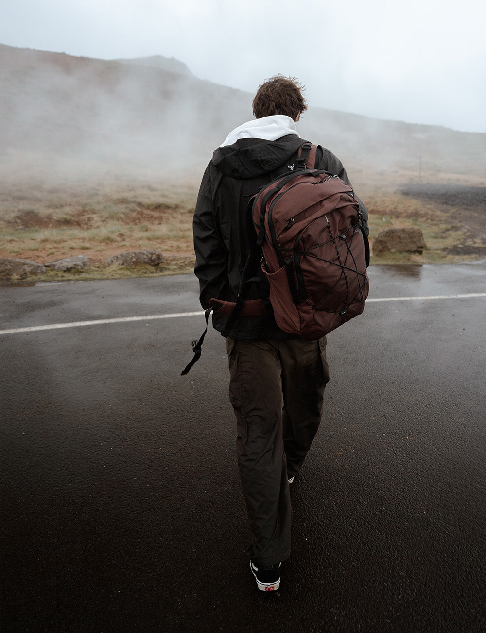 person with garnet backpack walking in rainy setting