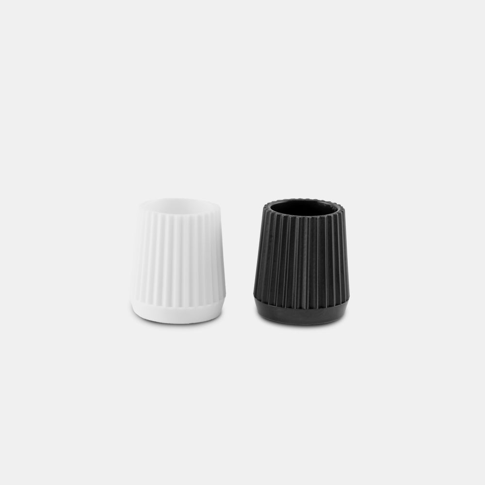 White and black refillable toothpaste tube lids side by side on light gray background