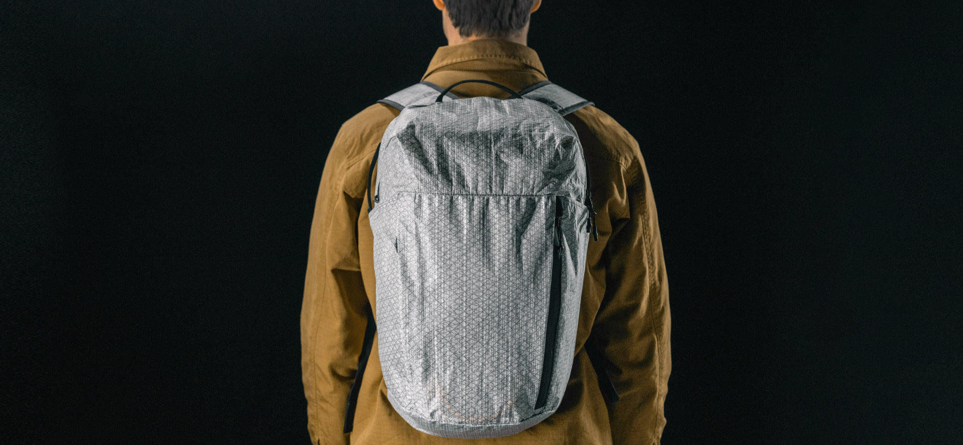 Man in black studio wearing white backpack