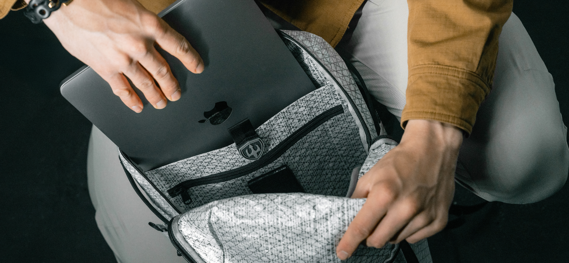 Man placing laptop into open backpack