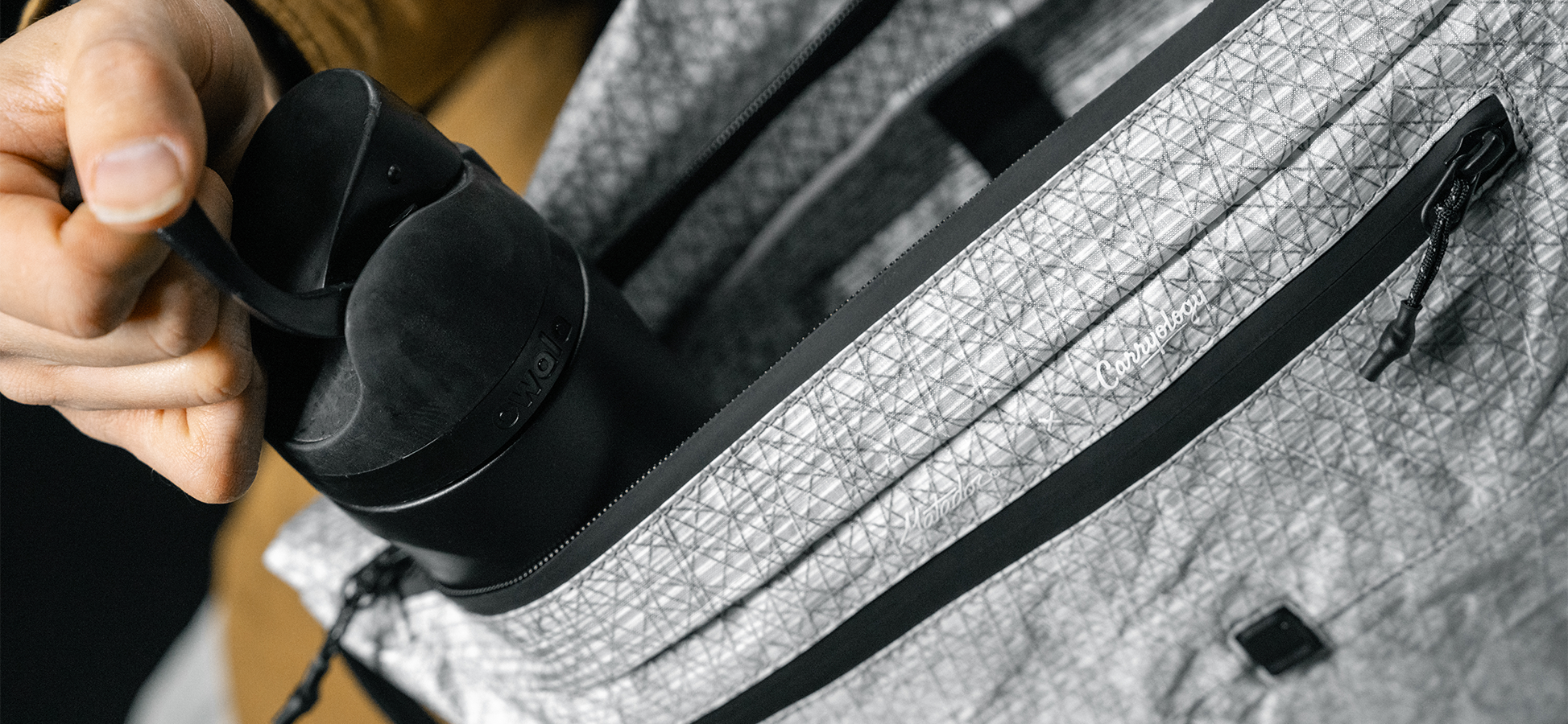 man pulling black water bottle out of white messenger bag