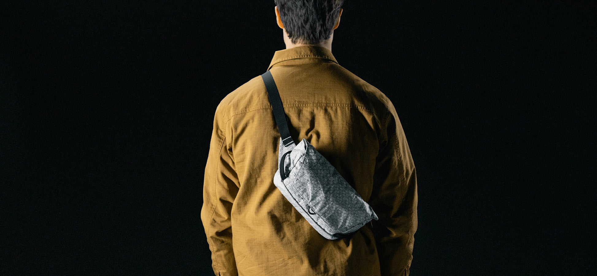 man in black studio wearing white sling across his back