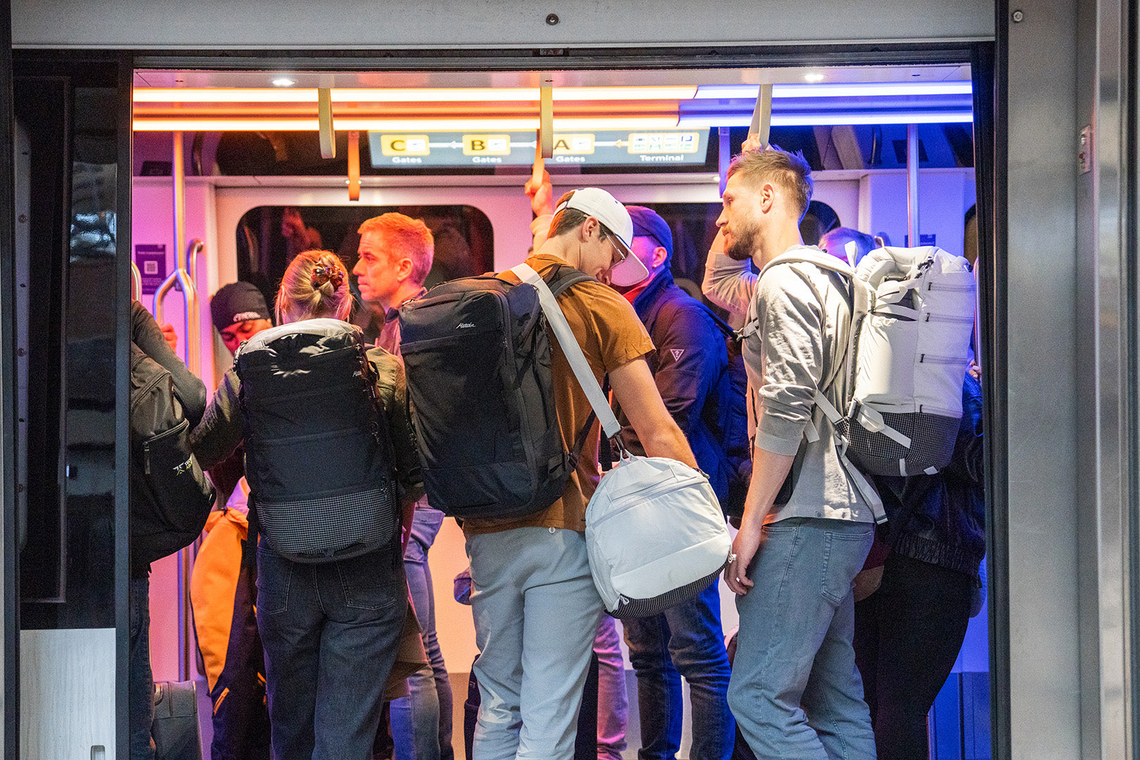 travelers standing on a train having a conversation about weatherproof vs waterproof backpacks
