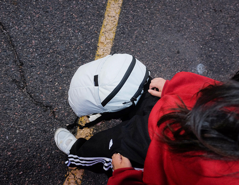 a person holding a water-resistant travel backpack in an urban parking lot
