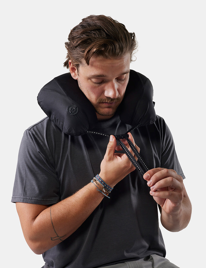 Man wearing a packable travel pillow against a white background