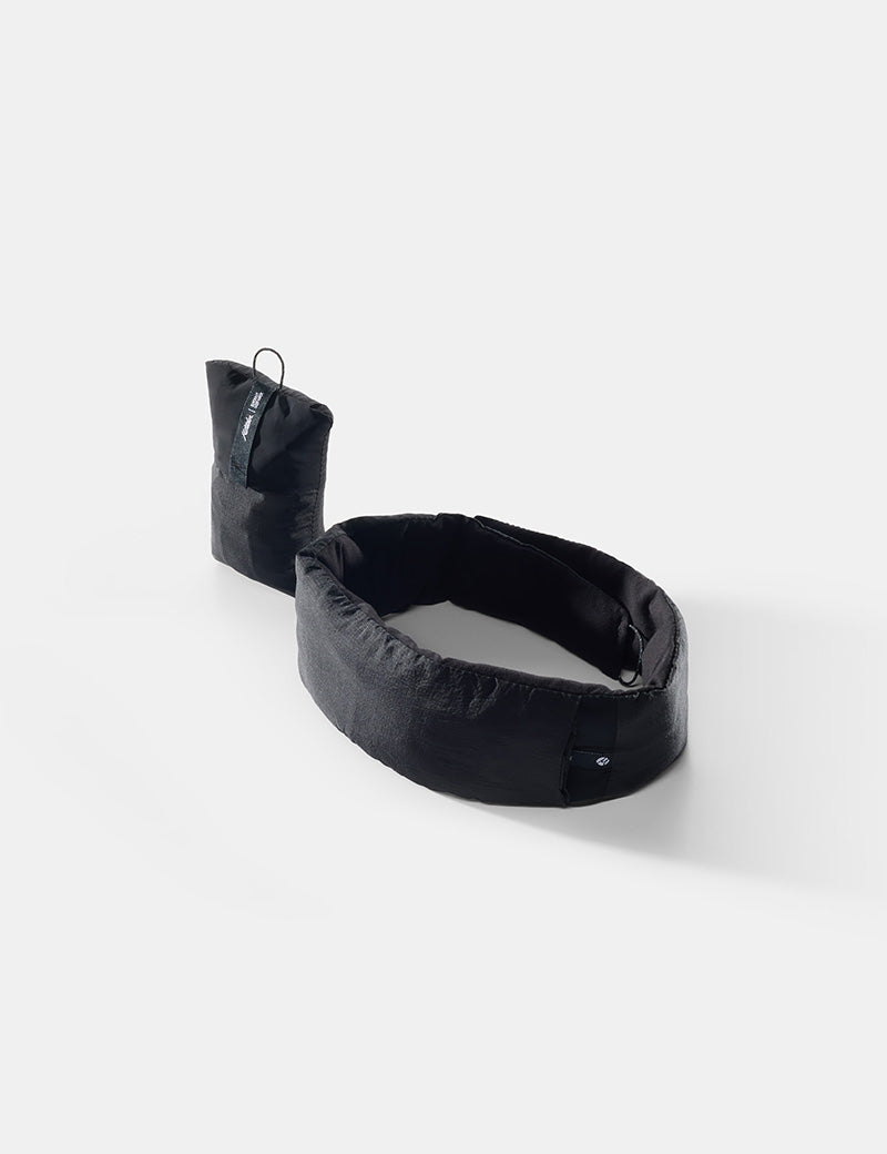Blackout sleep mask and earplugs next to a pouch with the mask and earplugs stored on a white background