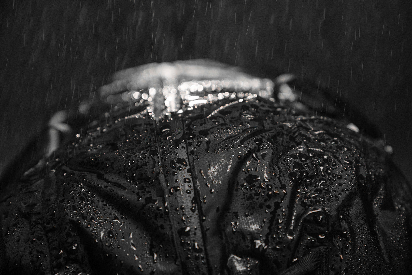 a travel bag getting rained on with water droplets beading on the outside of the duffle