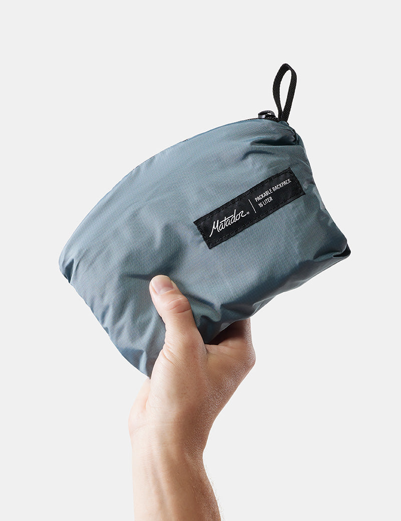 a packable backpack folded up and held by a hand