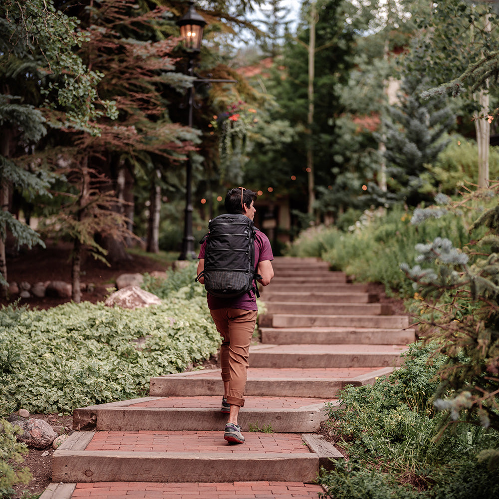 person at an international destination wearing a black SEG28 travel pack while walking up steps outside