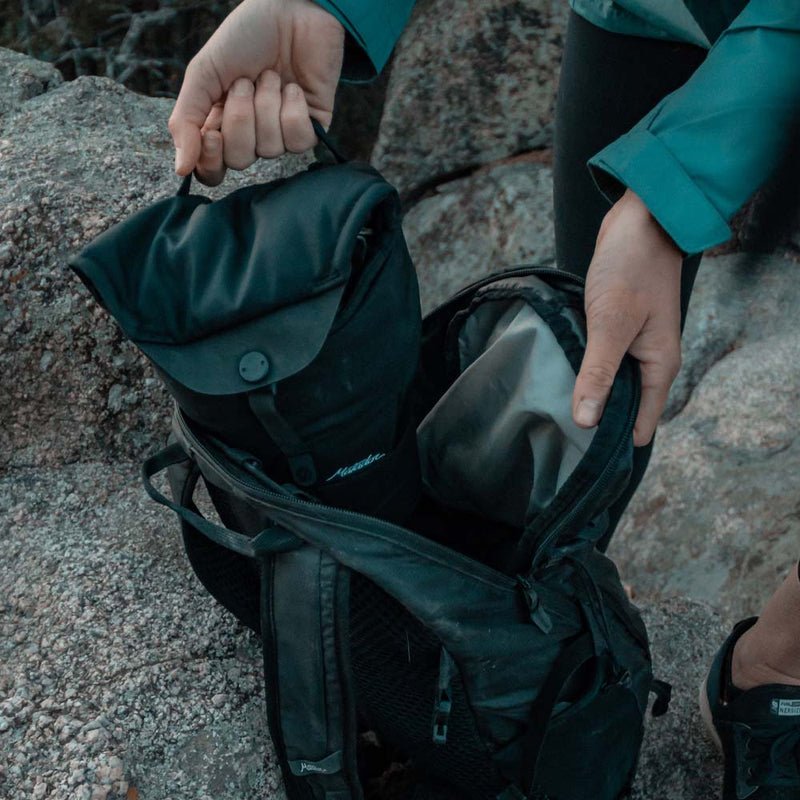 Woman placing camera base layer into backpack