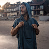 Man on beach, pulling charcoal poncho hood strings