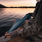 Woman next to a sunset lake, holding a Slate Blue NanoDry towel