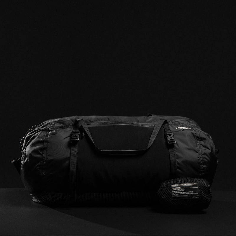 Front view of duffle and packed down pouch on black background