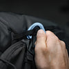 Hand attaching carabiner to backpack gear loop on black background
