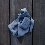 Slate blue NanoDry Trek Towel and silicone case laying on wooden dock