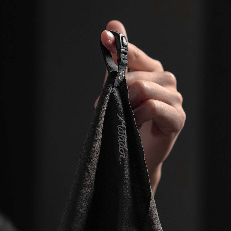 Close up view of the NanoDry towel's snap loop hanging from a woman's finger