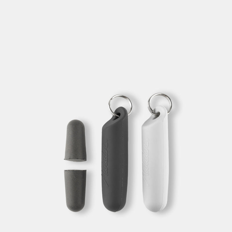 Gray earplugs next to gray and white silicone cases on light gray background