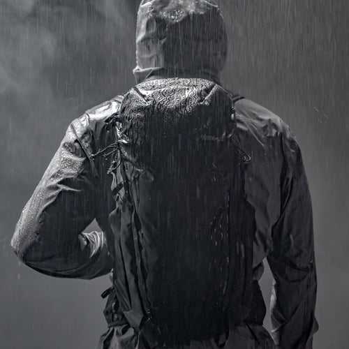 Back view of man standing in rain, wearing Beast28 backpack