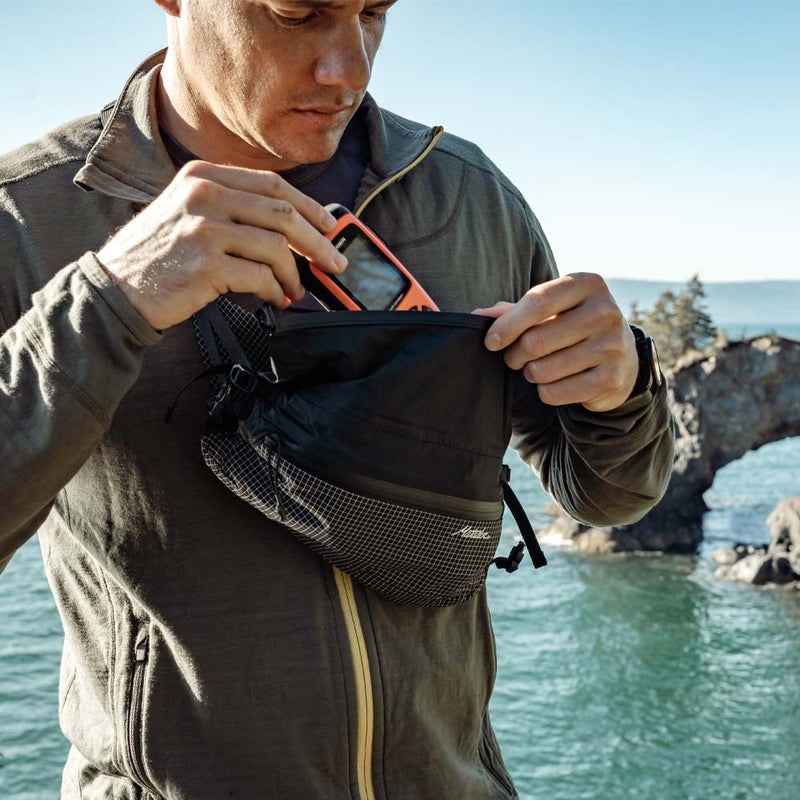 Man placing GPS device into cross body hip pack