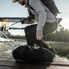Man on dock grabbing duffle from ground
