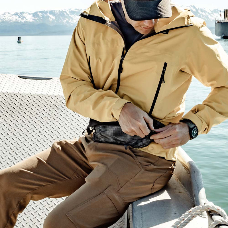 Man on boat, unzipping hip pack
