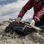 Woman on mountain, removing ice axe from gear loops