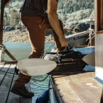 Man on dock with oars strapped to duffle