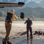 Man tossing duffle from sea plane to shore