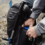 Man sitting in alpine tundra, removing water bottle from Beast28 pocket