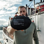 Man on dock, holding packed down duffle pouch