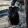Man holding waterproof backpack over ocean water
