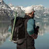 Man wearing backpack, looking out at Alaskan lake
