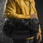 Man in pouring rain with duffle over his shoulder