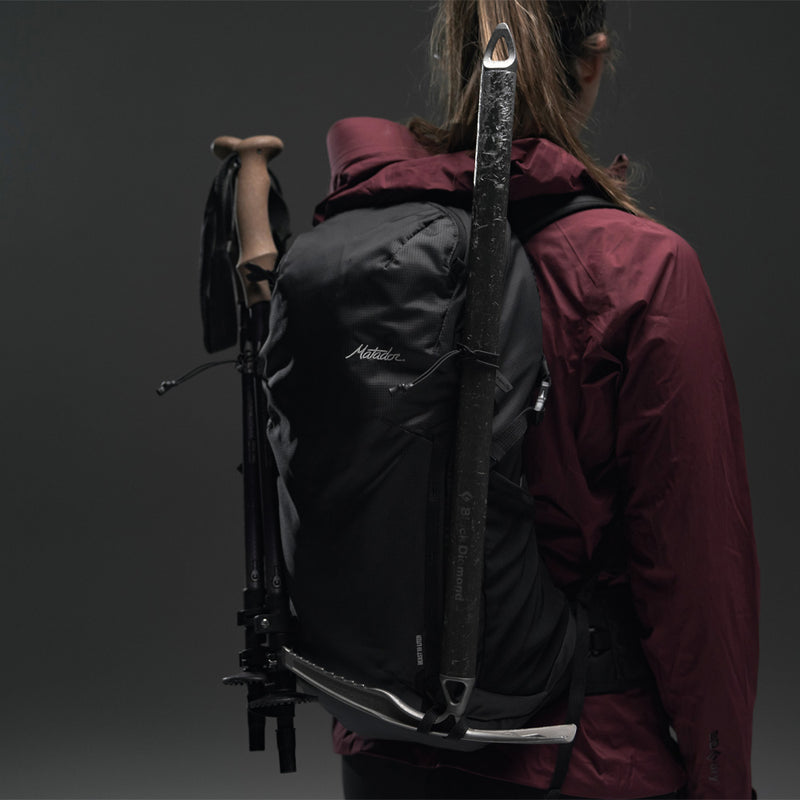 3/4 view of Woman wearing Beast18 with hiking poles and ice axe on gray background
