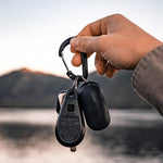 Hand holding keys with packed up Droplet keychain in front of an alpine lake