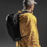 3/4 view of man wearing backpack on black background