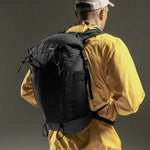 3/4 view of man wearing backpack on black background