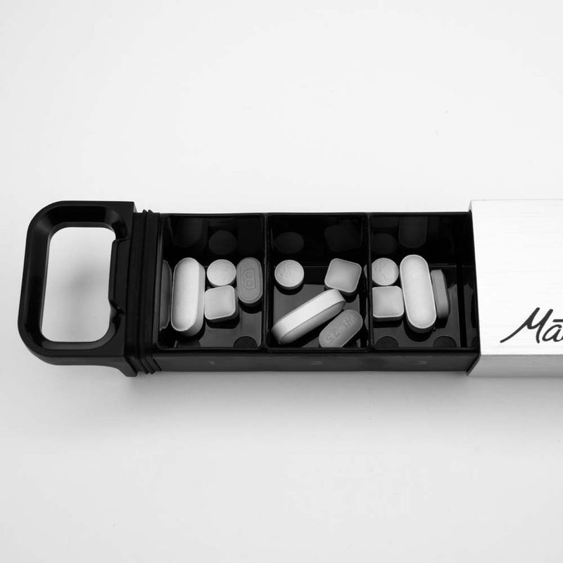 Close up view of pills in pill canister compartments on white background