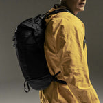 Side view of man wearing backpack on black background