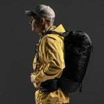 Side view of man wearing backpack on black background