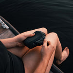 Woman sitting at dock pulling Charcoal NanoDry towel out of silicone case