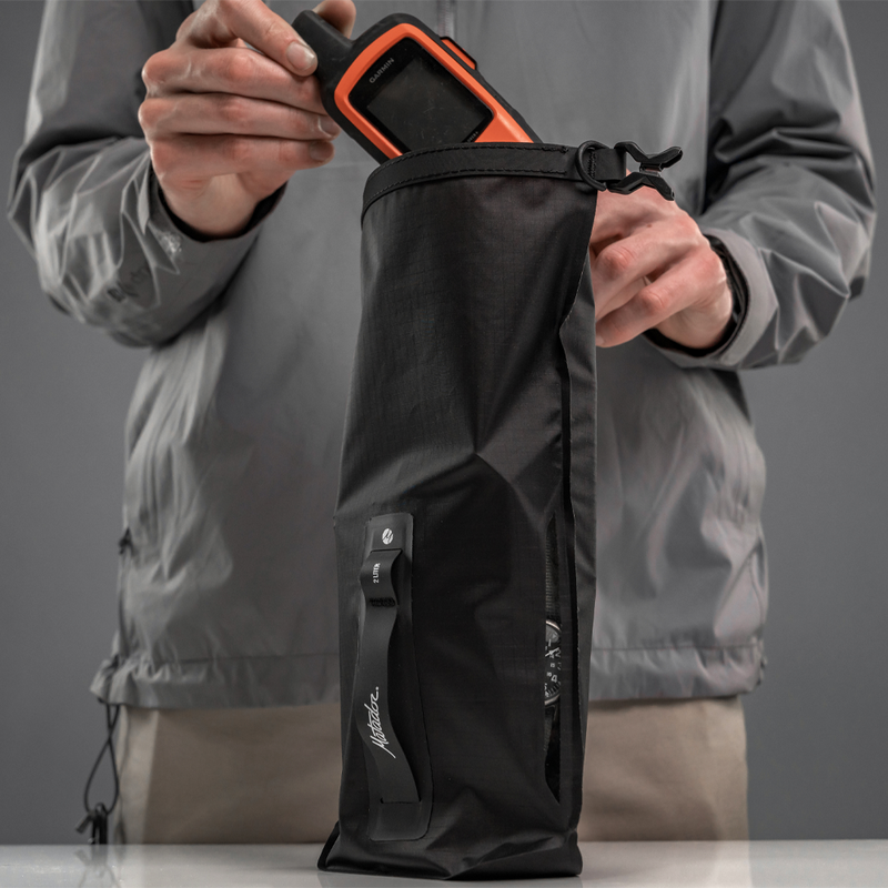 Man placing GPS device into dry bag