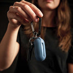 Woman holding keys with packed up blue Droplet keychain in front of black background