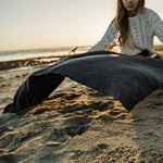Woman on beach, laying out charcoal beach towel