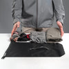 Man with Empty dry bag laid out next to folded socks, shirt, and pants